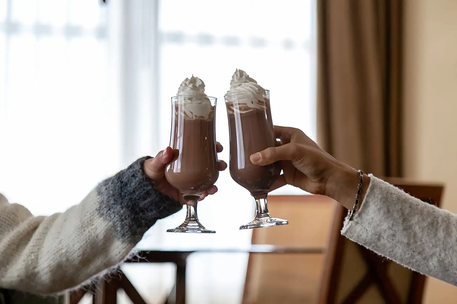 Two mugs of hot cocoa clinking